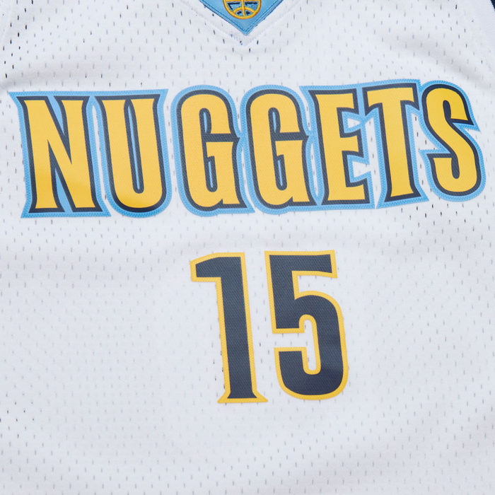 Up close view of front White basketball jersey with Nuggets in yellow with navy trim, trimmed in light blue and number '15' in navy with yellow outline on a white background