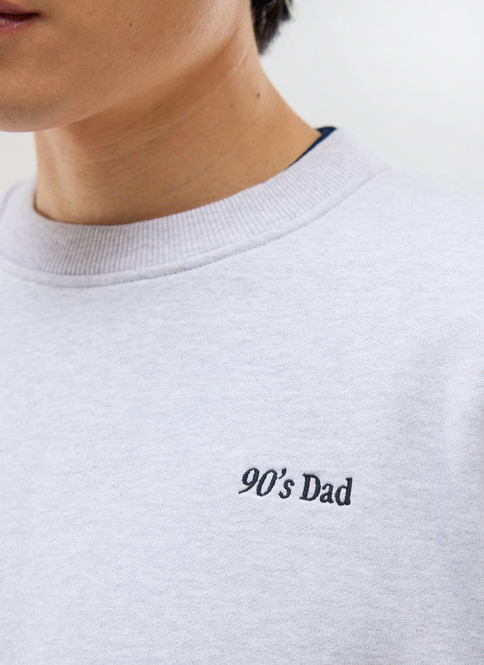 A close-up of the '90's Dad' embroidery on the chest of the athletic grey sweatshirt from Percival.