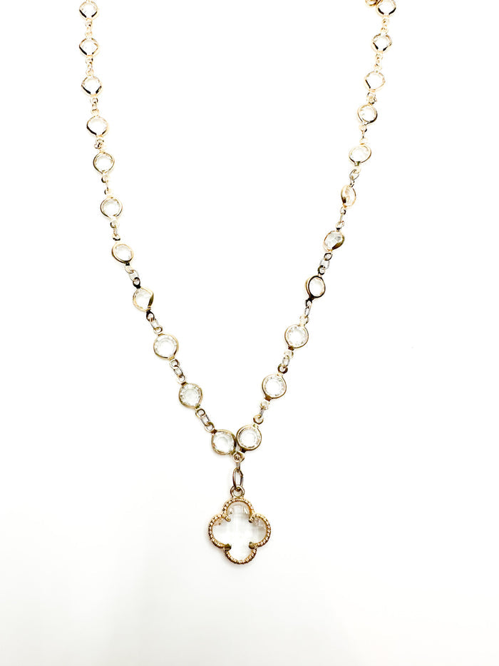 Gold necklace with a clover-shaped pendant on a white background