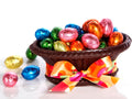 A basket made from molded chocolate holds chocolate eggs that are wrapped in brightly colored foil.