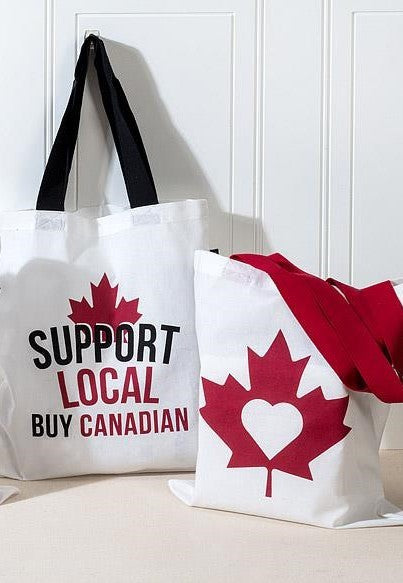 Two tote bags with a red maple leaf design and text on a white background