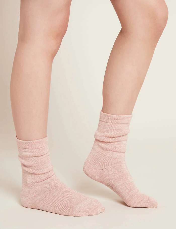 Pink socks worn by a person on a plain background