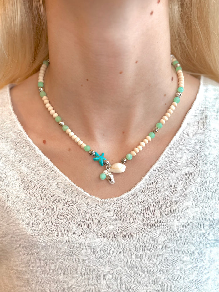 Coralie Charm Necklace with seafoam beads and coastal charms on models neck