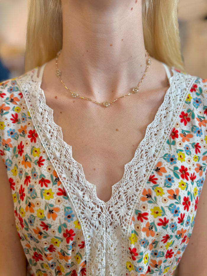 Daisy Floral Necklace in beige with gold-tone chain and beaded clusters on models neck