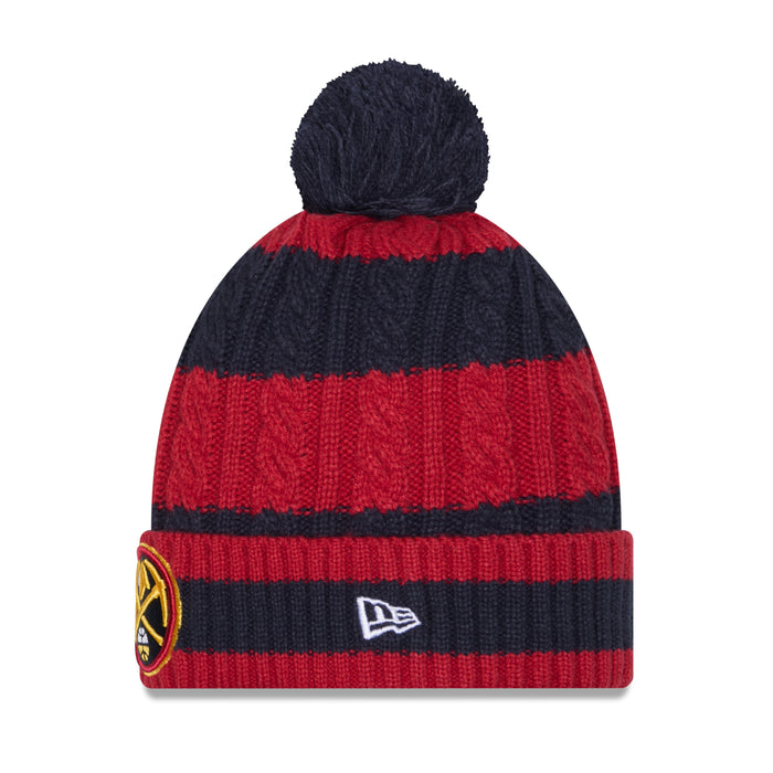 Left-side view of the striped winter pom beanie. This angle highlights the continuous navy and red cable-knit pattern stretching up to the fluffy navy pom-pom on top. On the ribbed fold-over cuff, a small, square white and silver New Era logo emblem is neatly embroidered, while the edge of the Denver Nuggets patch remains visible on the far left