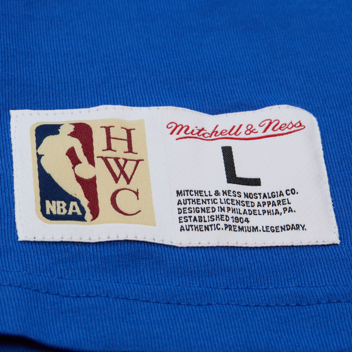 Close-up of a Mitchell & Ness Hardwood Classics woven jock tag with size L on a blue tank top