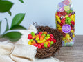 Colorful Jelly Beans in a bird's next with a bag of Jelly Beans behind it.
