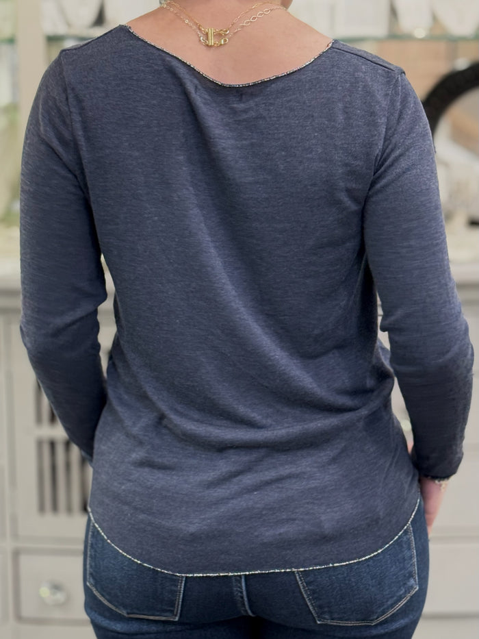 Back view of a lightweight navy knit top with curved hem and fine texture, worn with medium-wash jeans.
