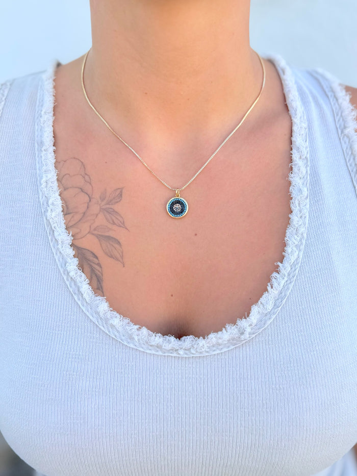 Necklace with a circular pendant featuring colorful stones being worn