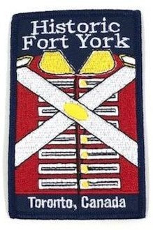 Navy blue iron on badge with embroidered image of Red Coat in centre. Historic Fort York embroidered in white at top. Toronto, Canada emroidered in white at bottom.