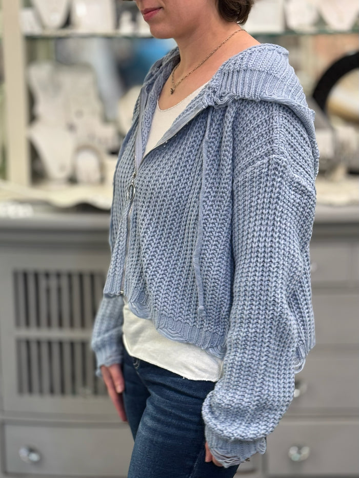 Person wearing a blue knitted hoodie in an indoor setting