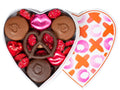 Chocolate covered oreos, pretzel, nonpareils and foil wrapped molded foil wrapped lips sit inside a fun X and O patterned heart shaped box.