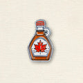 Maple syrup bottle with a red maple leaf on a textured beige background