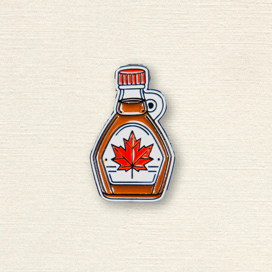 Maple syrup bottle with a red maple leaf on a textured beige background