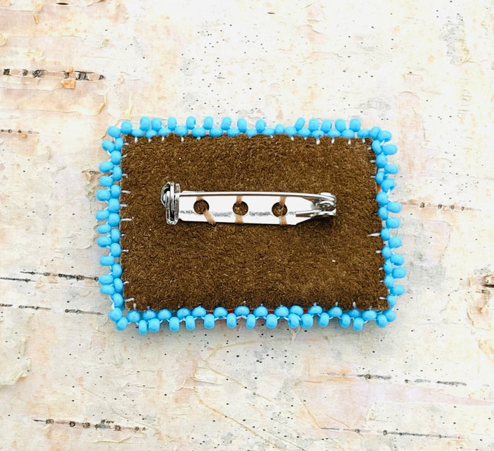 Back of beaded orange shirt pin showing suede backing and brooch pin