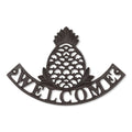 Cast iron sign with a pineapple over the word "welcome"