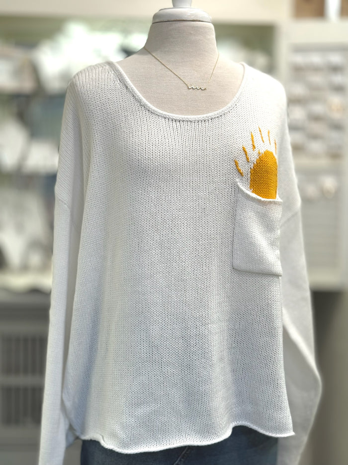 Cream open-knit scoop neck sweater with Sun design poking out of front chest pocket from Ardor Boutique