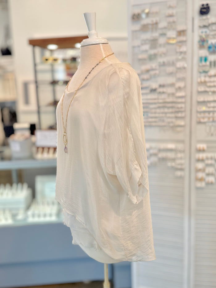 Beige blouse on a mannequin in a store setting