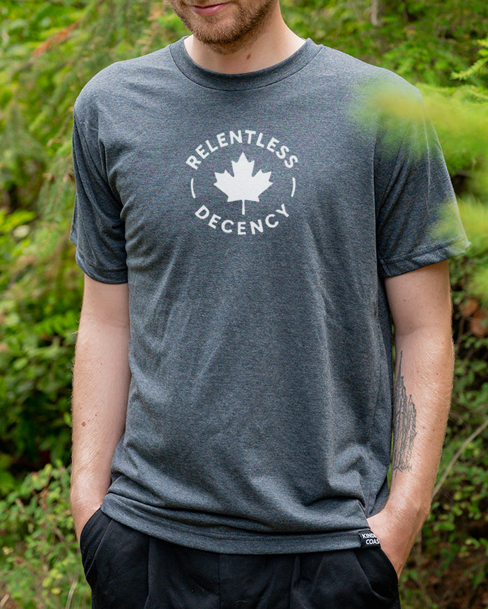 Man wearing a gray t-shirt with a logo and text outdoors