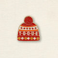 Pin of a red toque with 'TOQUE' text on a textured beige background