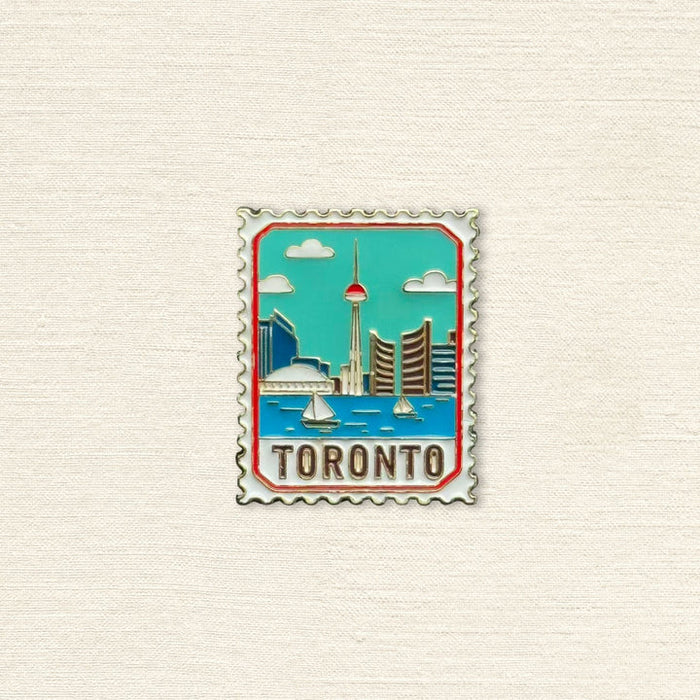 Enamel pin with Toronto skyline design on a textured beige background