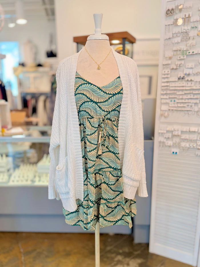 The Trina Dress in Tropical Green styled with cozy white knit cardigan and gold necklace for a layered spring look